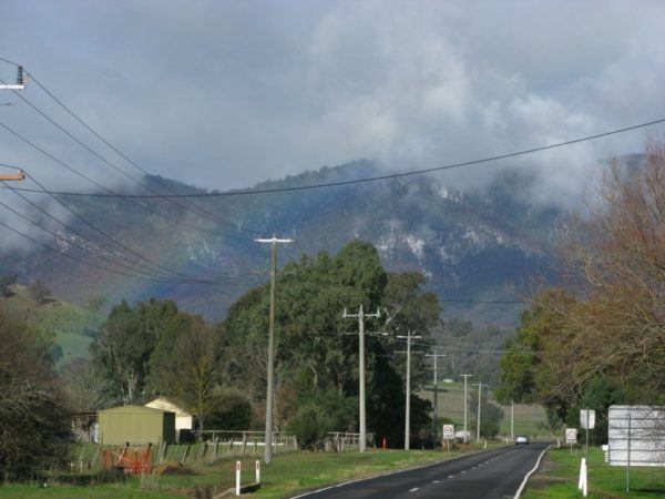 snow in Australia, gracing the mountains behind a rainbow