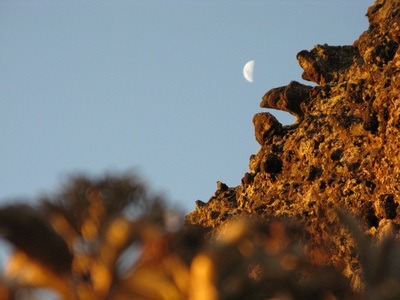 sunset against a cliff with a bright half moon