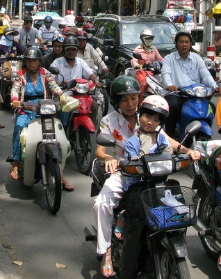 How to cross the road in Saigon? Walk slowly and predictably, and the Busy motorcycle traffic in Vietnam will go around you 