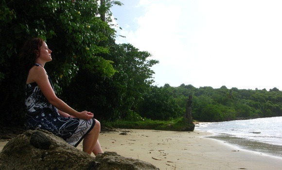 Nora Dunn, The Professional Hobo, meditating on a beach while spending three months in Grenada