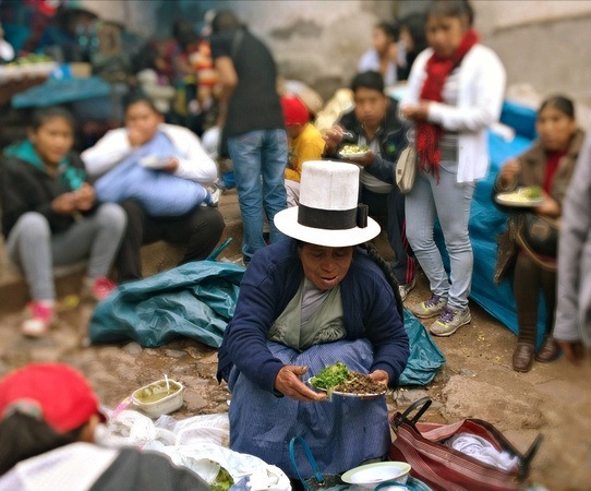 Andean woman selling lunch at a busy market in Cusco