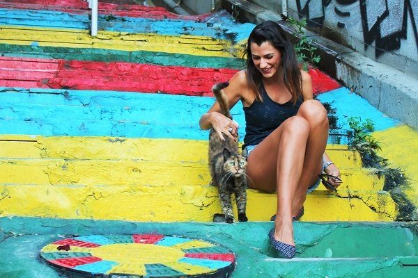 Nat of Love and road sitting on a colourful staircase petting a cat