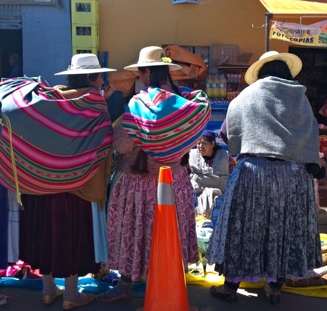 3 ladies buying fabric in the marketplace between the border of Peru and Bolivia