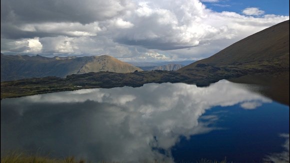 Andean lake mirroring the sky with clouds