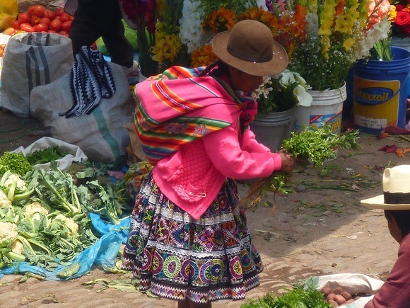 Andean woman with colourful clothing and bowler hat at a fresh market in Pisac