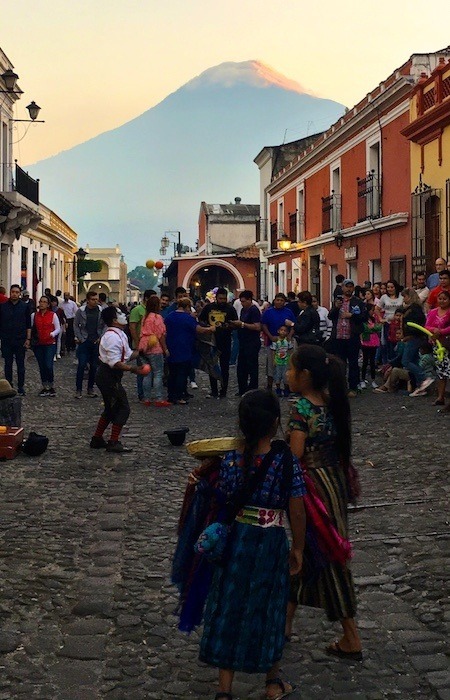 Things to do in Antigua Guatemala include walking around the town centre, with vendors, buskers, and a volcano in the background