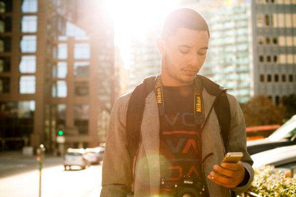 Man using phone in city - How to Use Your Phone Internationally Without Charges