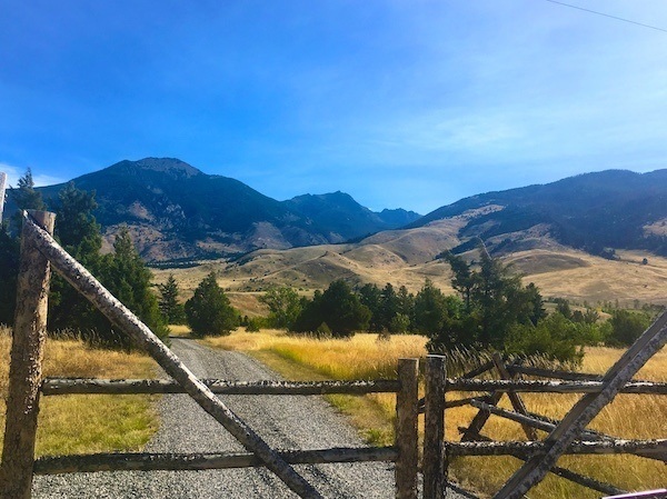 Montana Ranch Entrance with fence in front and mountains behind, and neighbours far far away!